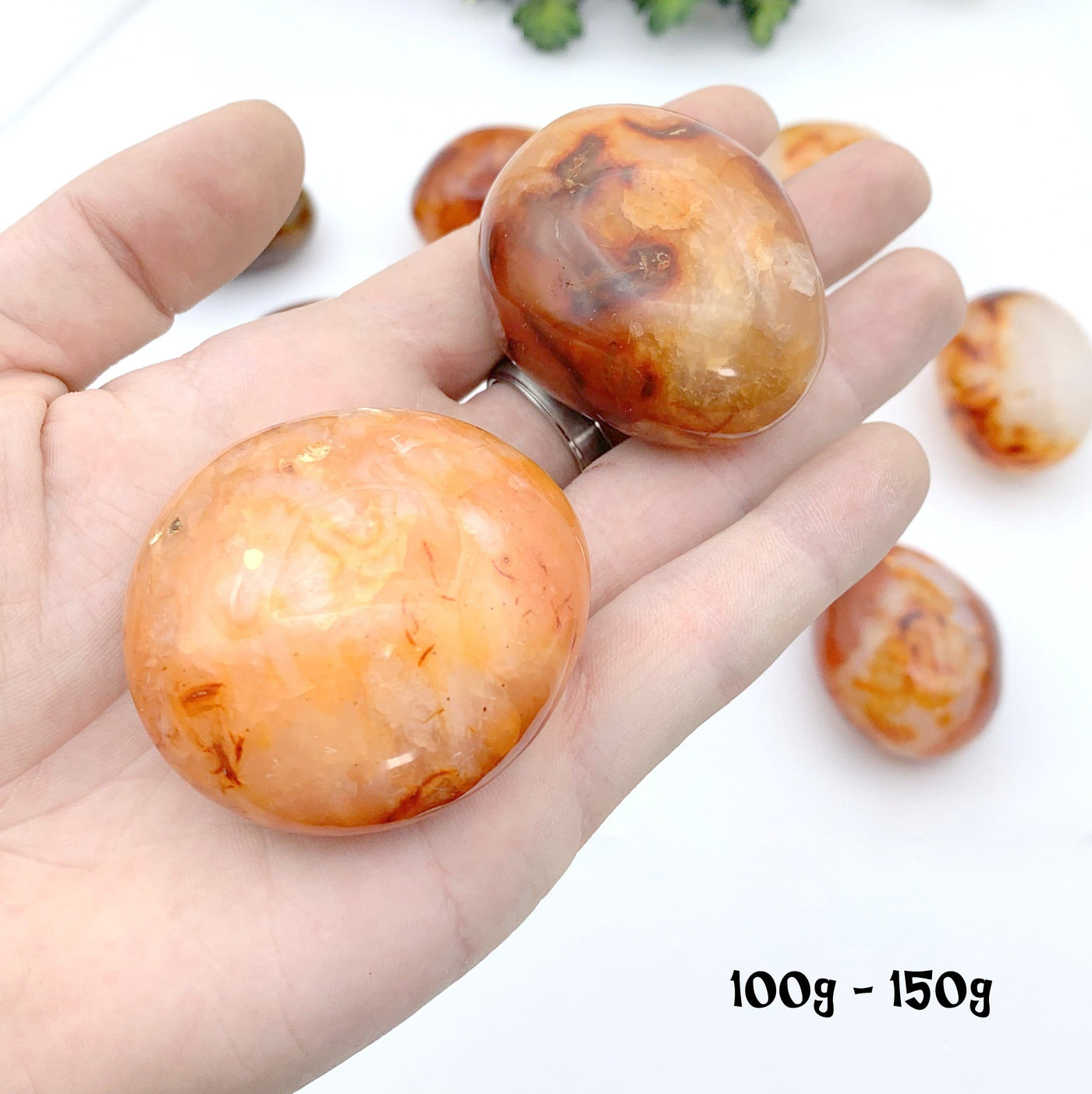 2 100 gram to 150 gram carnelian stones in hand with a white background