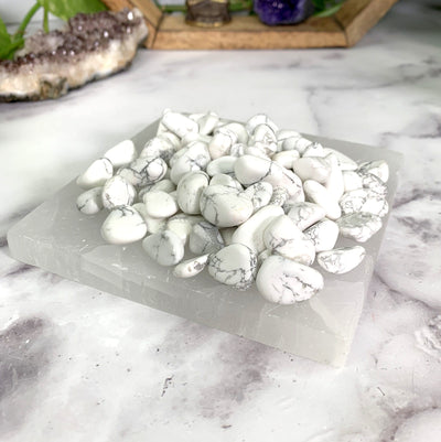 angled shot of howlite on selenite slab with decorations in the background