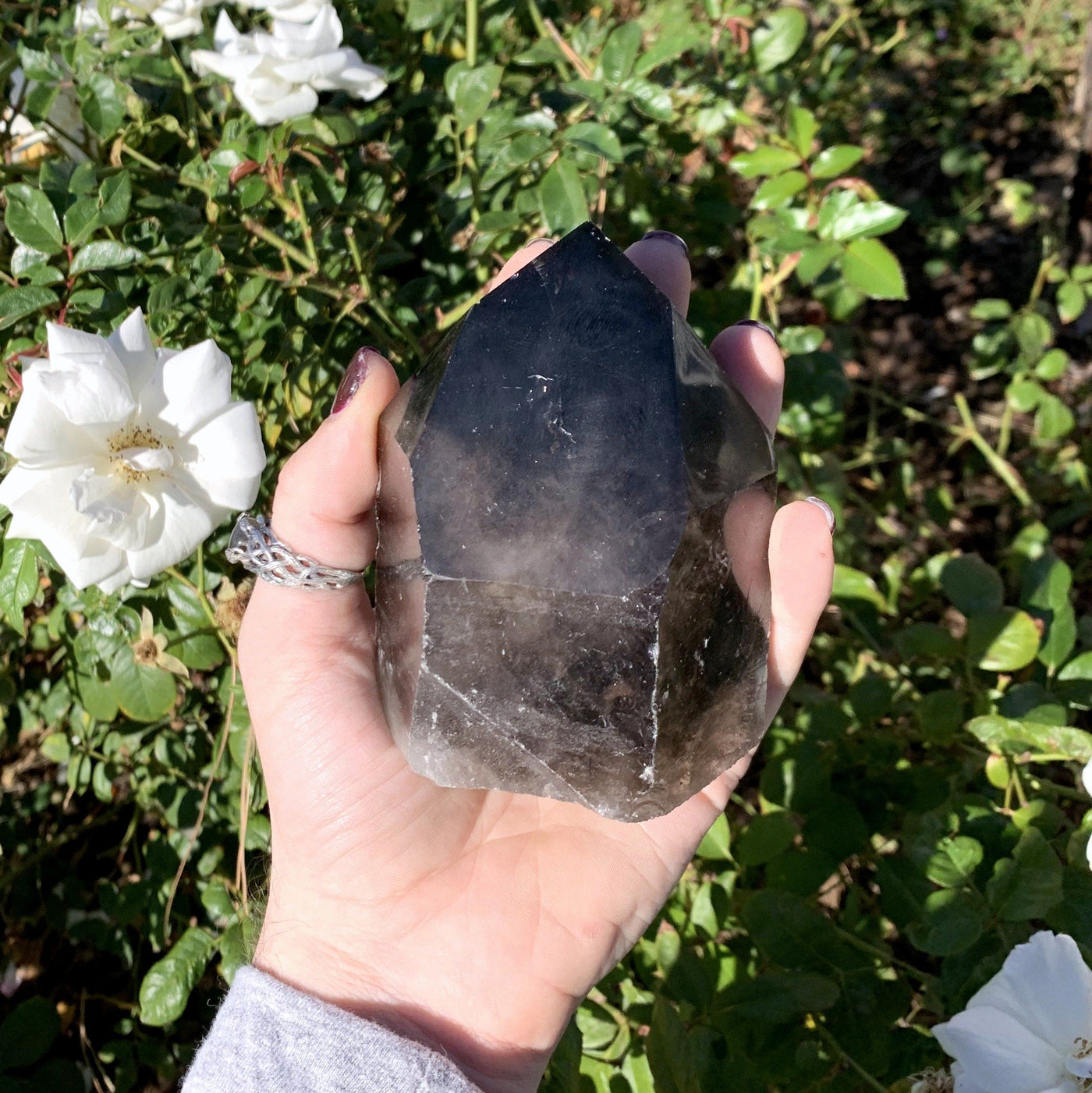Smoky quartz point in hand with floral background