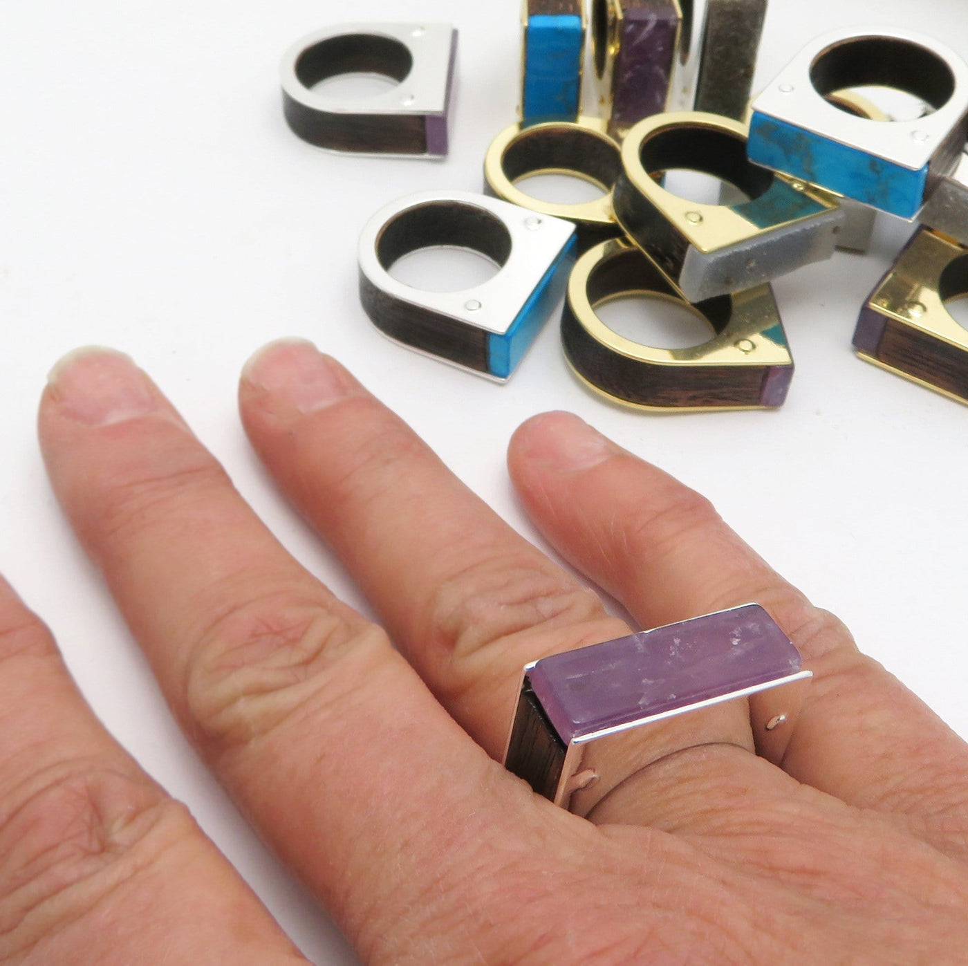 Amethyst rectangle ring with silver plating and wood insert on band on a woman's hand.  Turquise and druzy rings pictured in the background