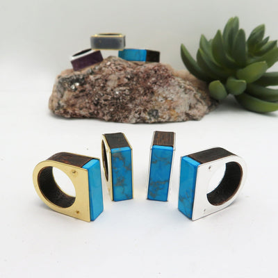 4 assorted turquoise howlite rings on a white background.