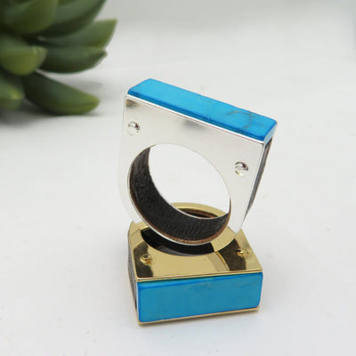 A gold plated and silver plated Turquoise howlite ring on a white background.