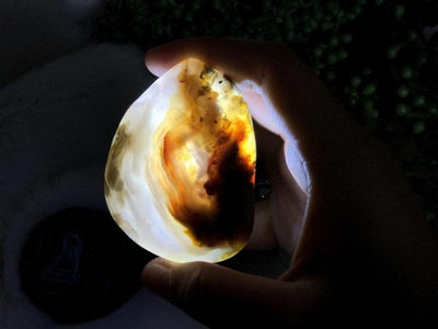 A Enhydro Polished Agate Geode in hand showing how it looks with the light off