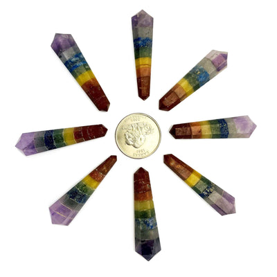 multiple double terminated points that are chakra themed next to a quarter for size reference 