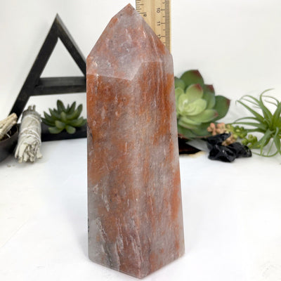 full view of the hematite quartz polished tower point with a ruler showing size