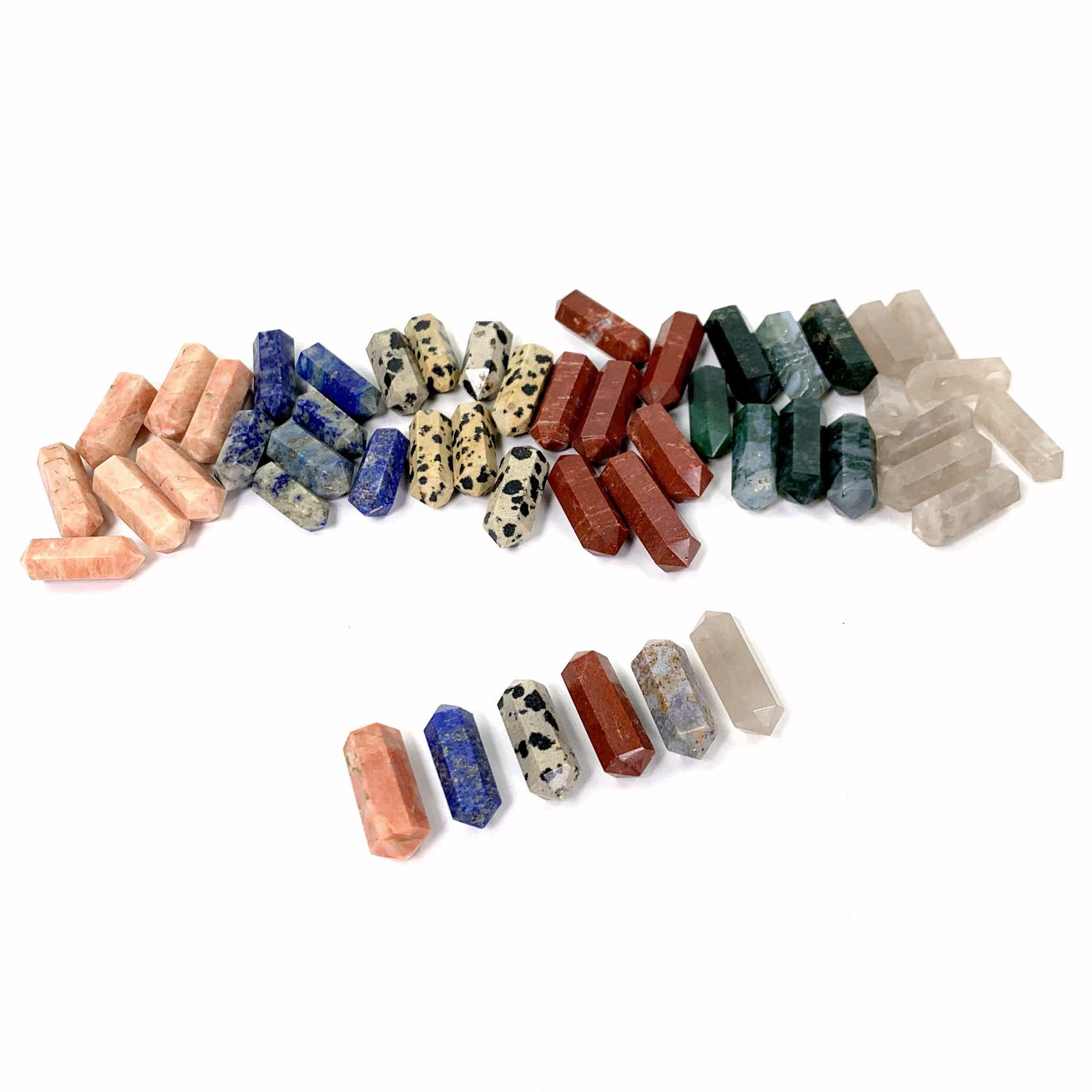 6 Piles of Gemstones With a Single Gemstone From Each in a Line in Front on White Background.