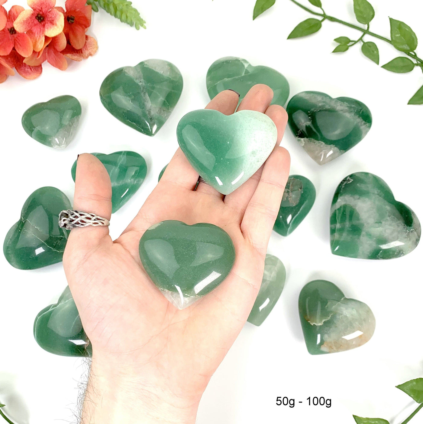 two 50g - 100g green quartz hearts in hand with a white background