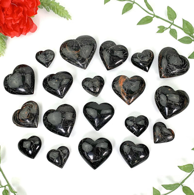 19 black tourmaline hearts laid on a white background