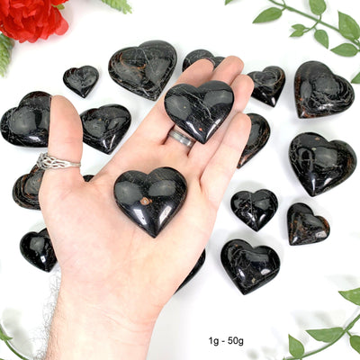 2 1gram - 50gram hearts in hand above a white background