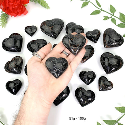 2 51gram - 100gram hearts in hand above a white background