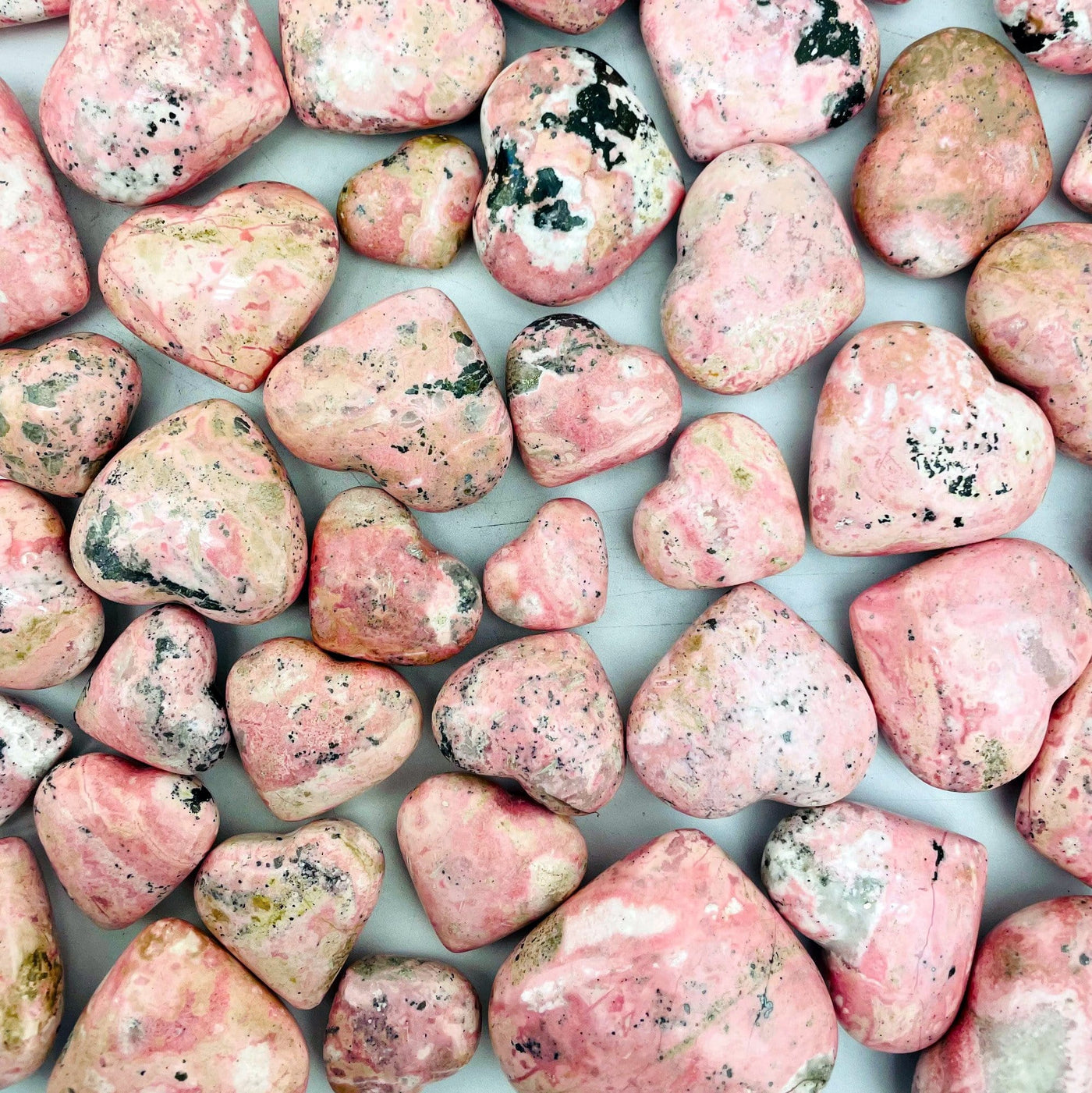 Rhodonite Hearts scattered on gray background