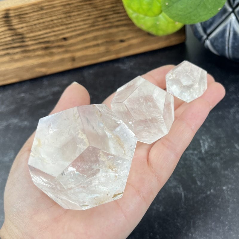 close up of multiple crystal quartz dodecahedron shaped stones in hand 
