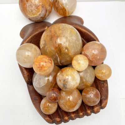 hand shaped bowl holding golden healer polished spheres