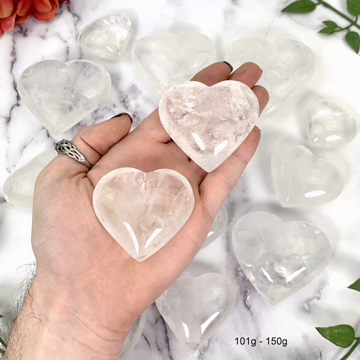 Crystal Quartz Hearts--2 101gram-150gram hearts with inclusions in hand with with multiple hearts in background.