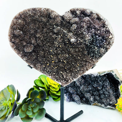Black amethyst heart on a black metal stand on a white background.
