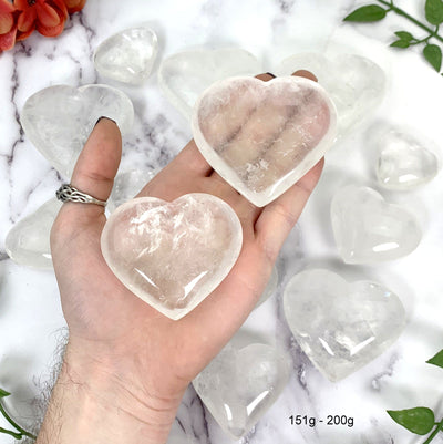 Crystal Quartz Heart--2 151gram-200gram hearts in hand with a white marble background