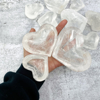 the 3 sizes of Crystal Quartz Heart Bowls in hand for size reference