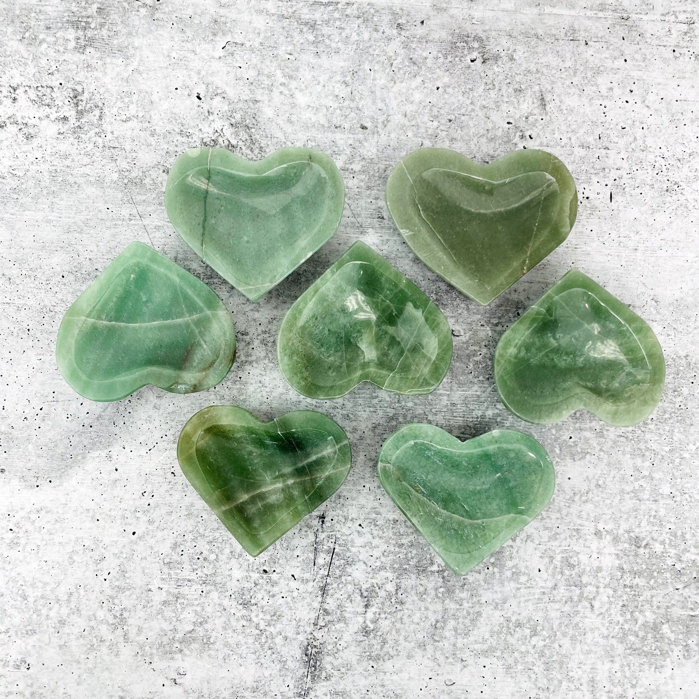 multiple Green Aventurine Stone Heart Dishes top view on grey white background