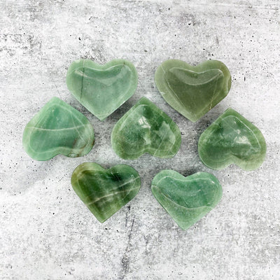 multiple Green Aventurine Stone Heart Dishes top view on grey white background