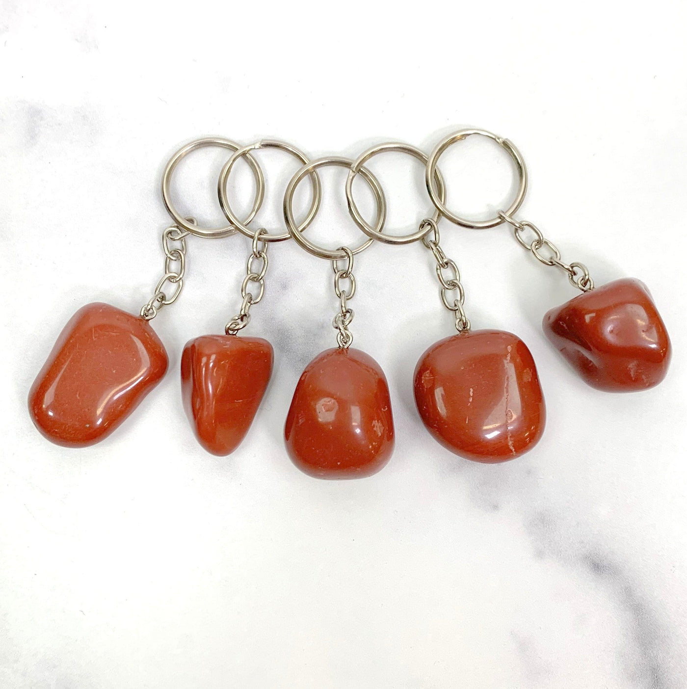 multiple Tumbled Red Jasper silver Keychain links and ring on white background showing various shapes and sizes