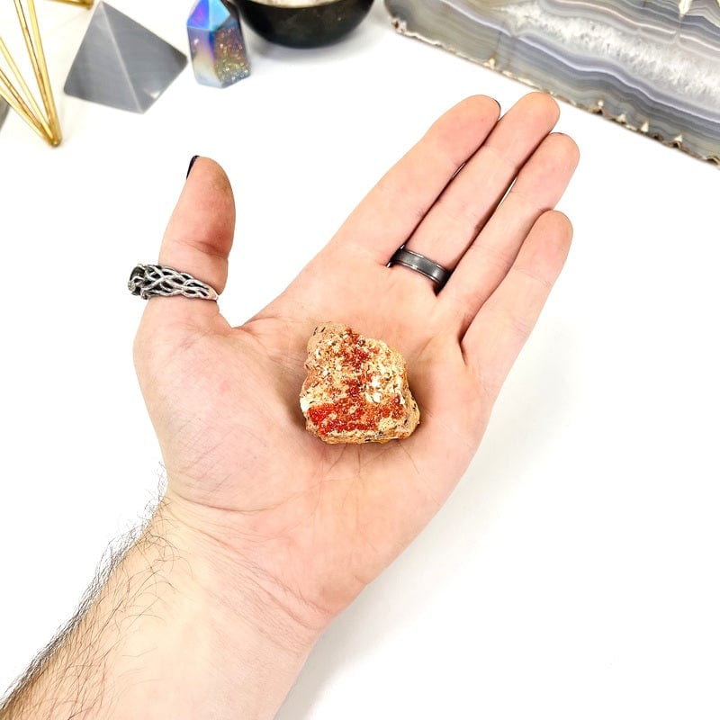 bottom view of vanadinite cluster in hand with white background