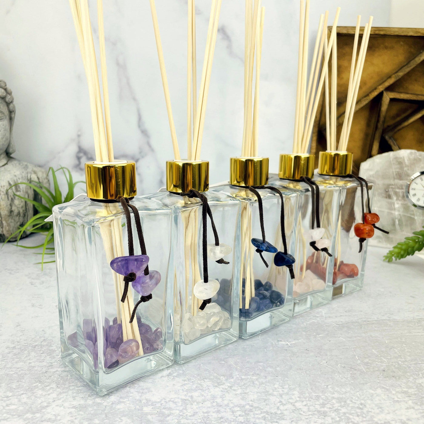 Tumbled Stone Diffuser Bottle--side shot view of stones inside glass bottle with wooden sticks and string with stones hanging on the side.