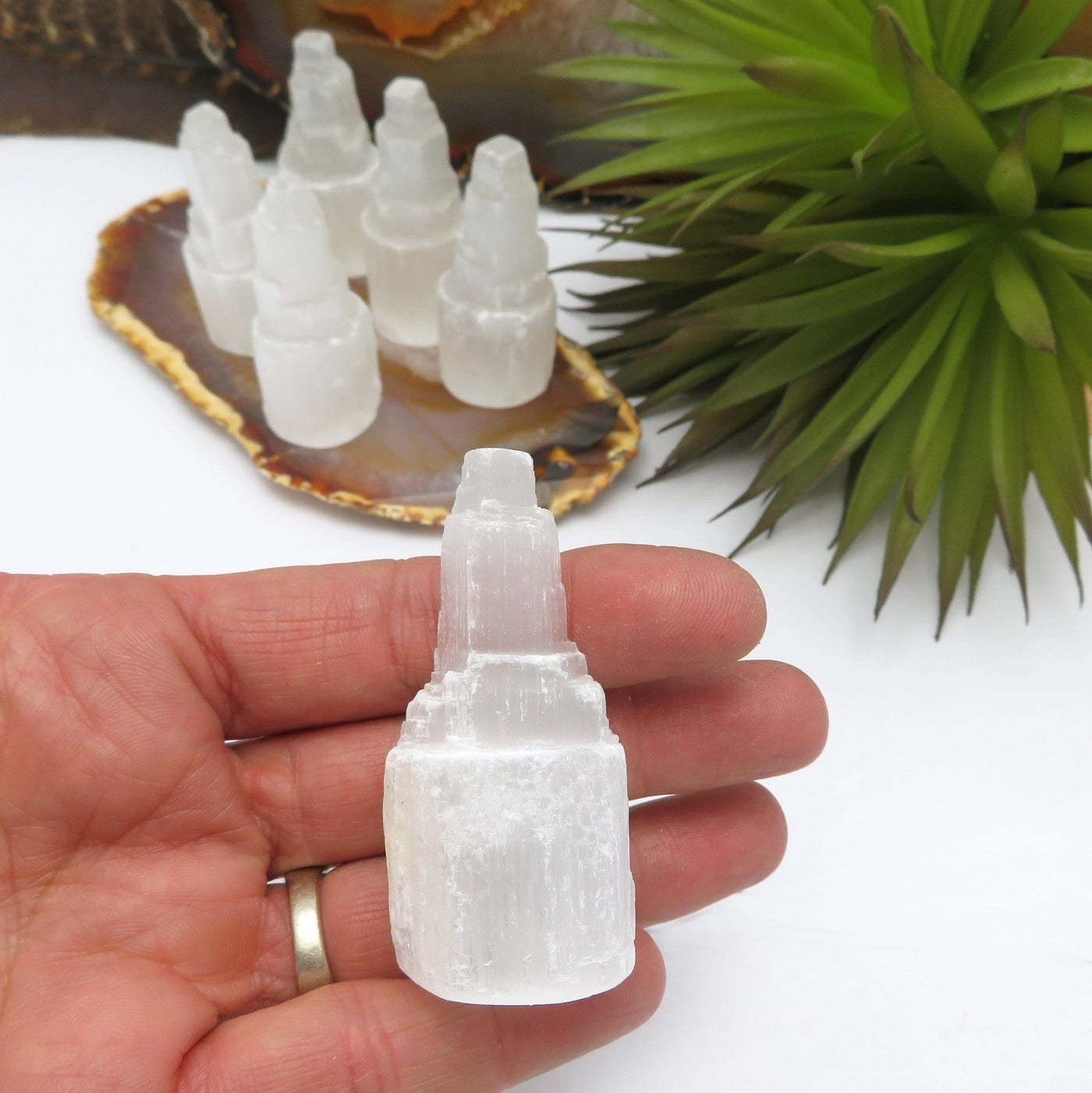 selenite raw crystal tower in hand for size reference with others in background display