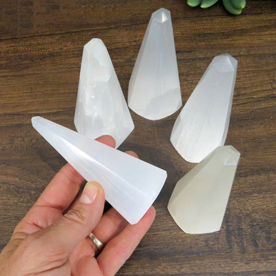 selenite polished obelisk in hand for size reference with others on display in background