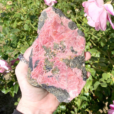 Rhodonite stone in hand with floral background
