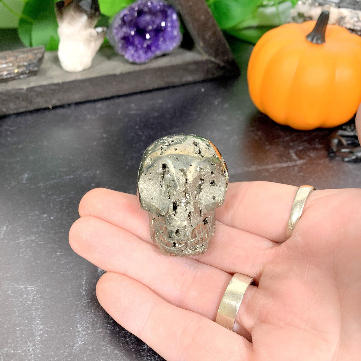 hand holding up Pyrite Skull with decorations in the background