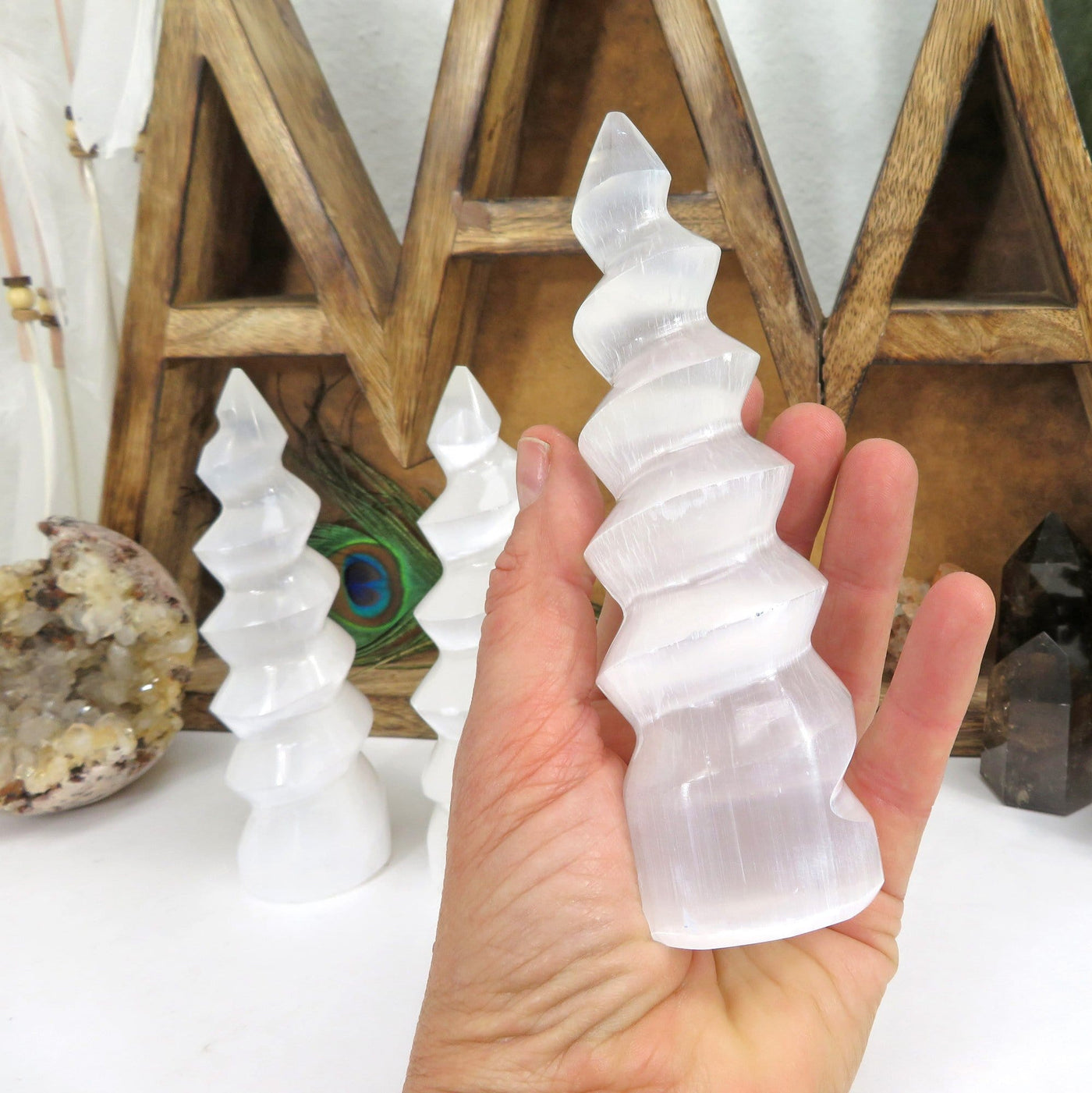 selenite spiral tower in hand for size reference with others in background display