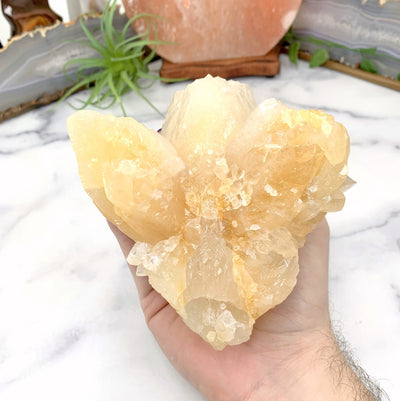 bottom view of calcite cluster in hand with marble background