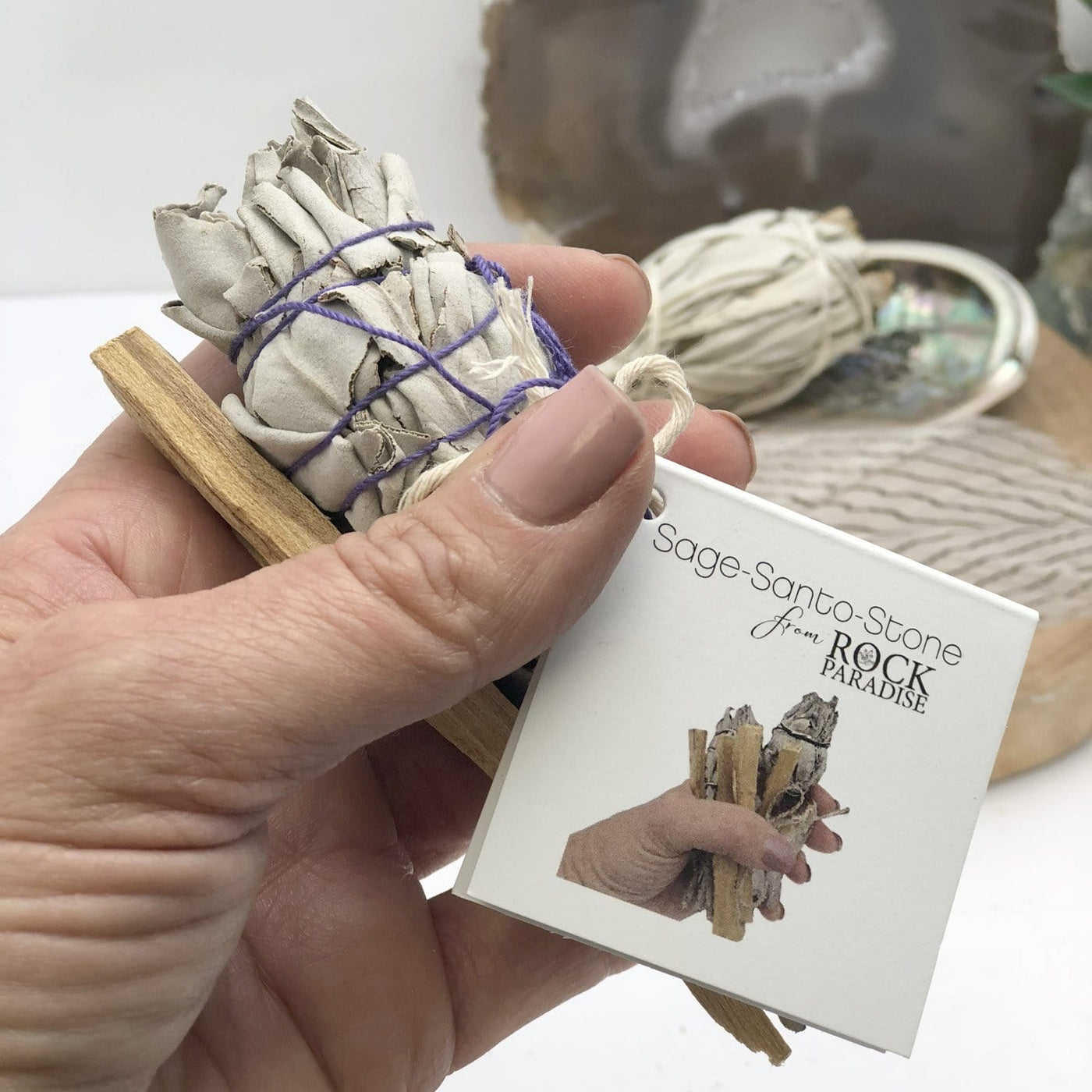 sage bundle palo santo with assorted stone and tag in hand for size reference