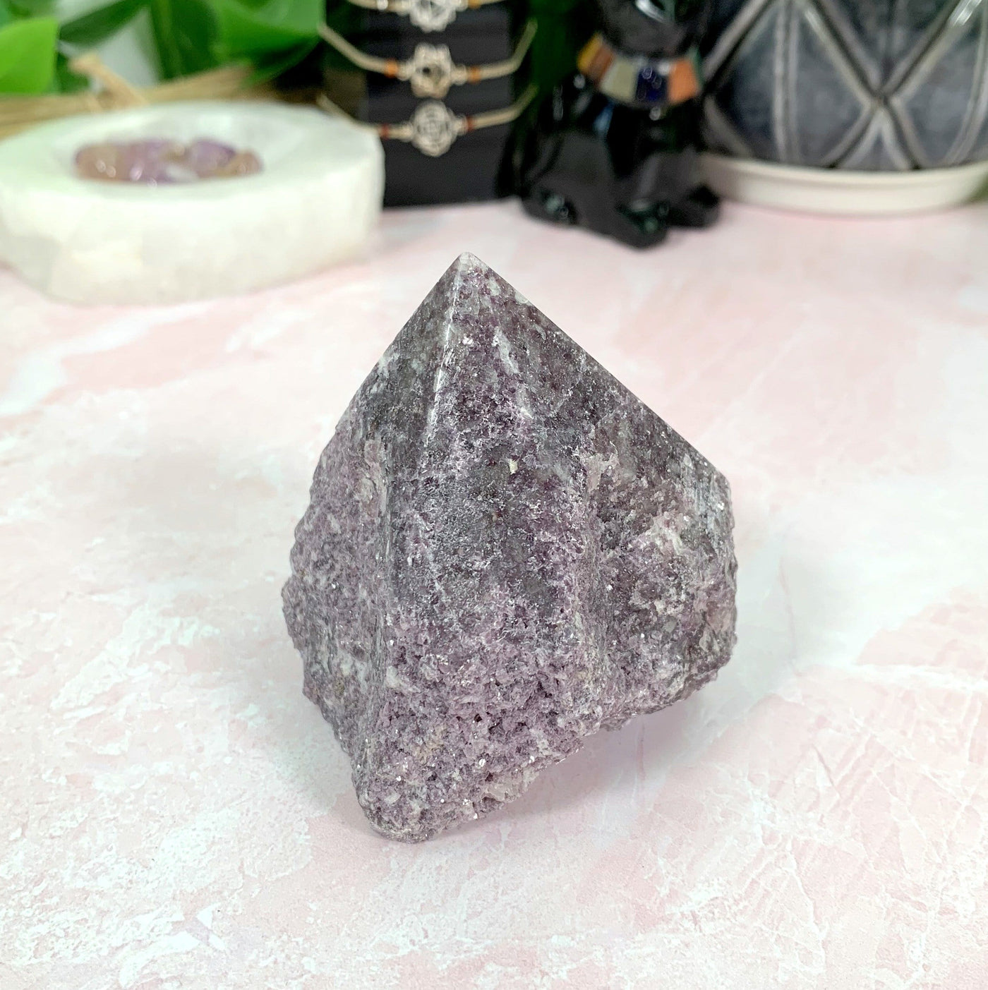 Lepidolite Semi-Polished Point with decorations in the background