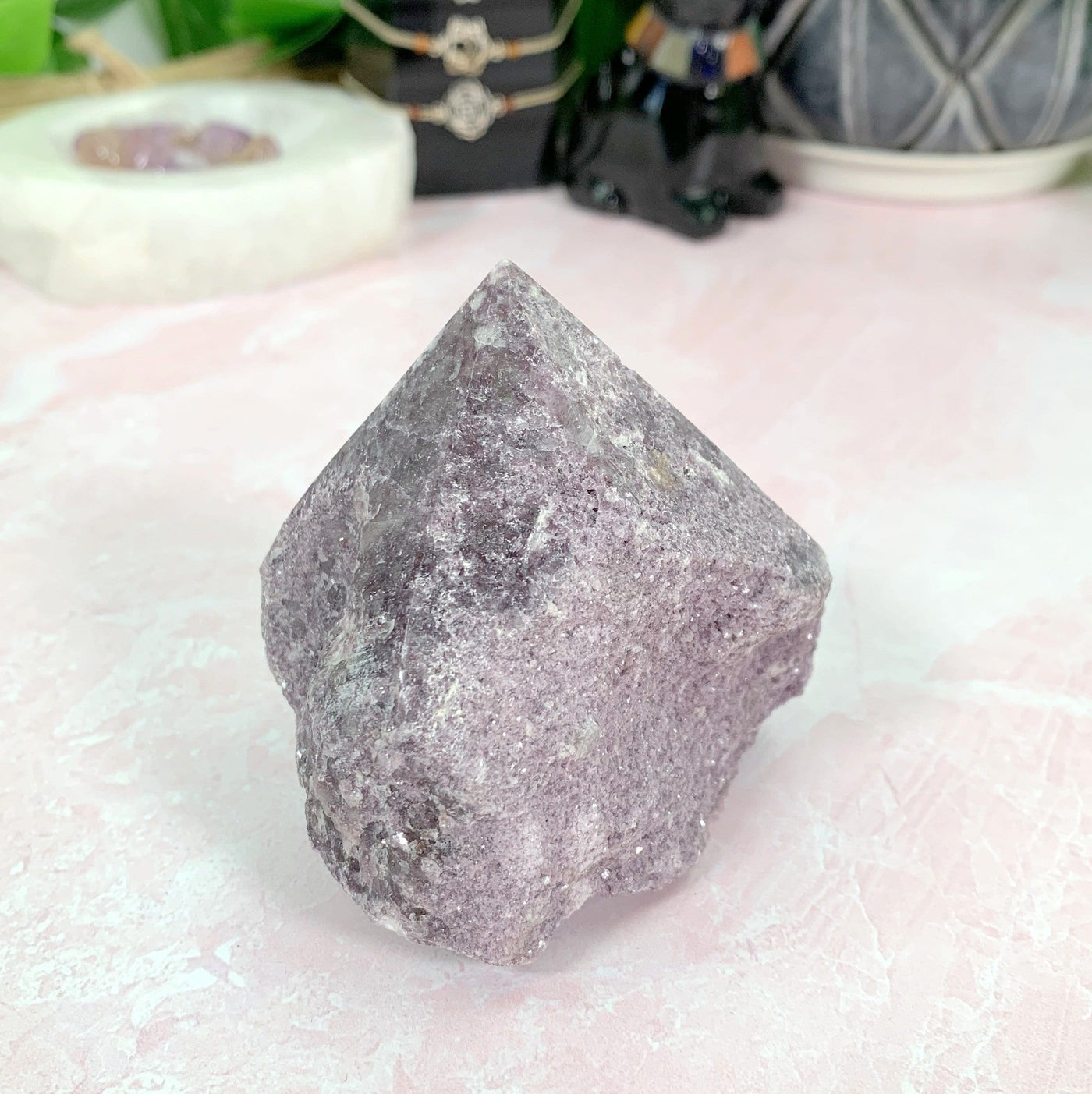 Lepidolite Semi-Polished Point with decorations in the background