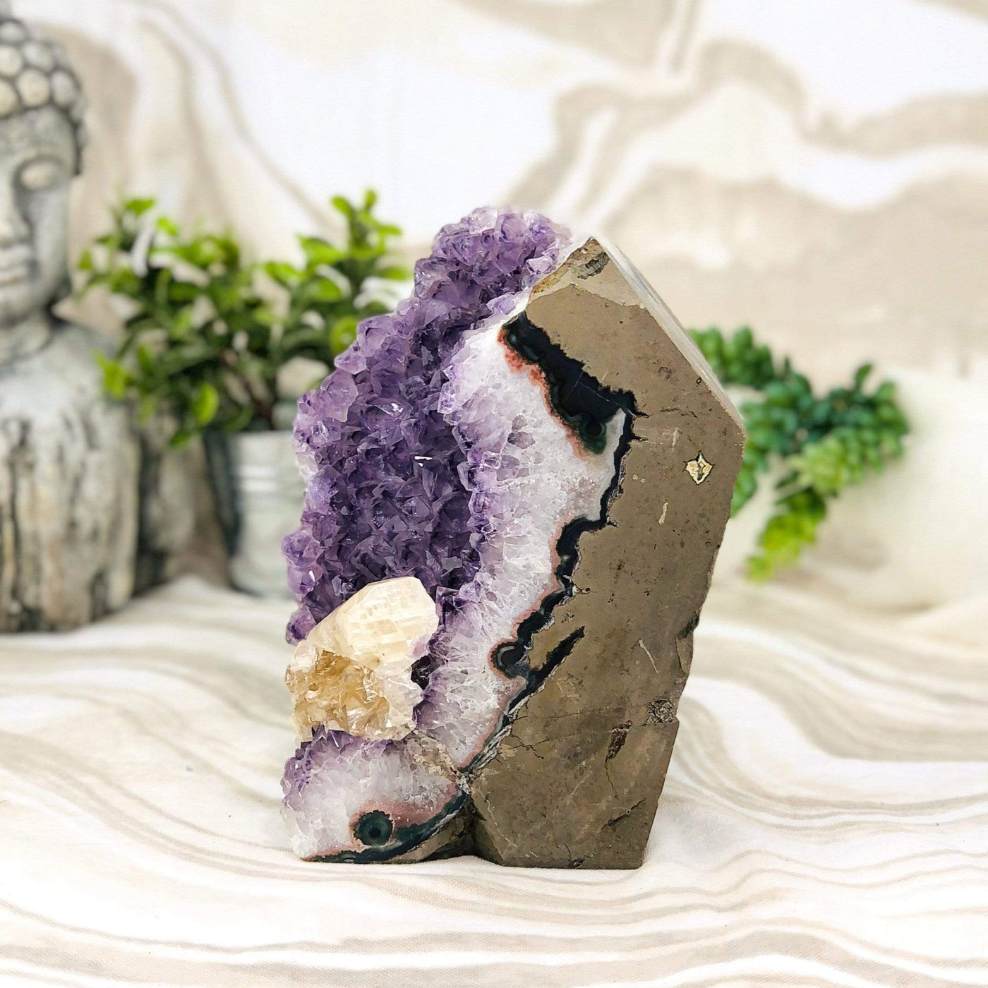 side view of Amethyst Cluster with Calcite with decorations in the background