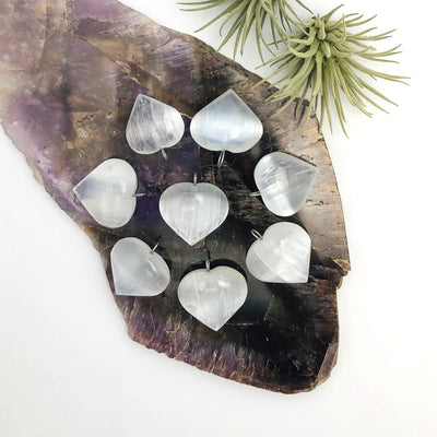 many selenite heart pendants on display for possible variations