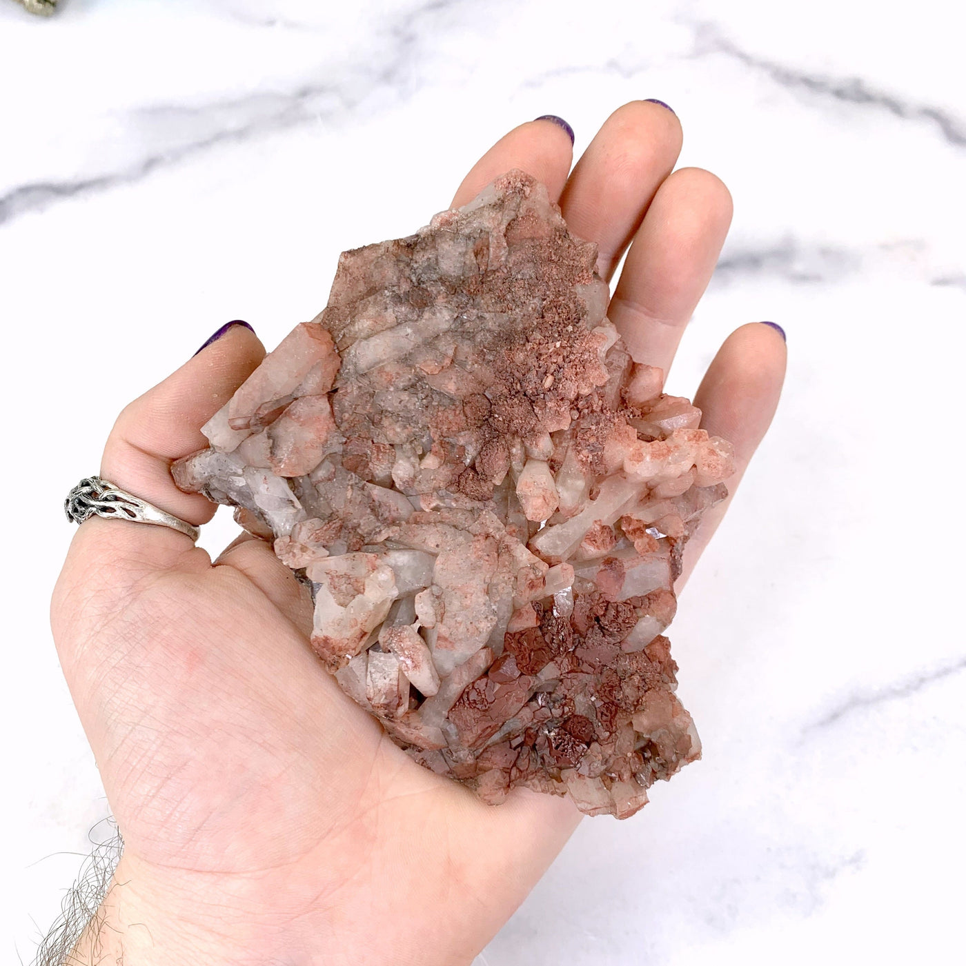 bottom of lithium quartz in hand with marble background