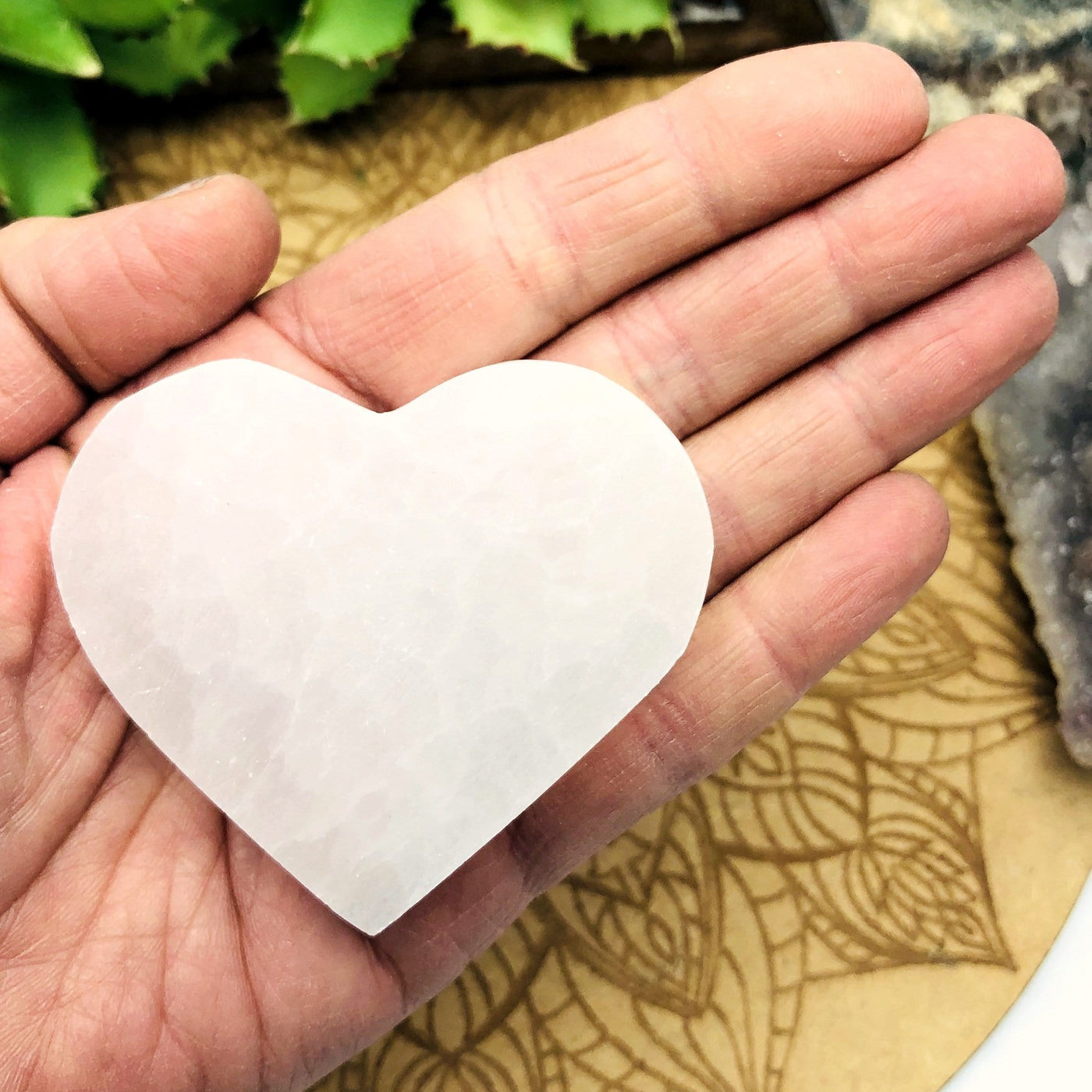 selenite flat heart in hand for size reference