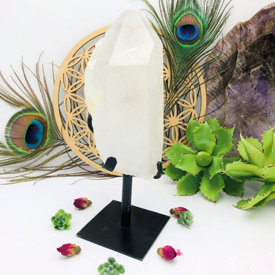 Crystal Quartz Point Stone on Metal Stand with decorations in the background