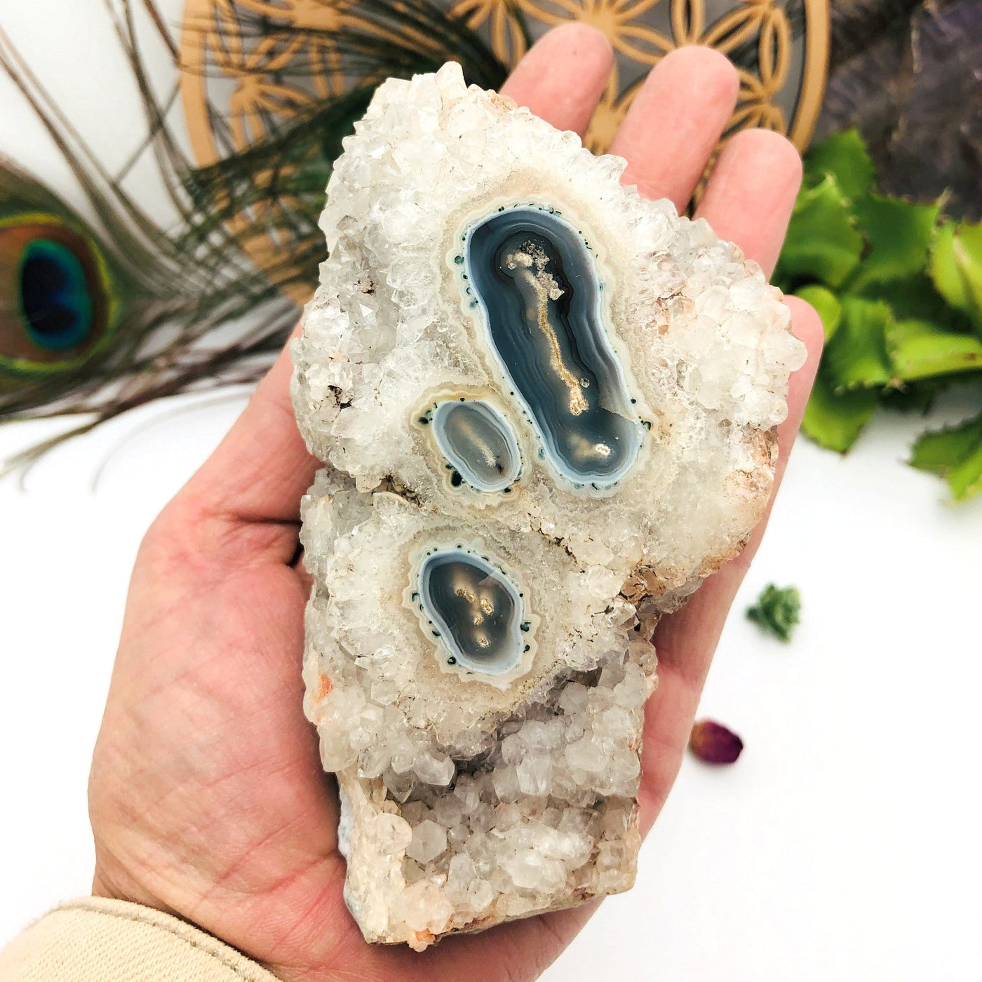 hand holding up Amethyst Stalactite Cluster with decorations in the background
