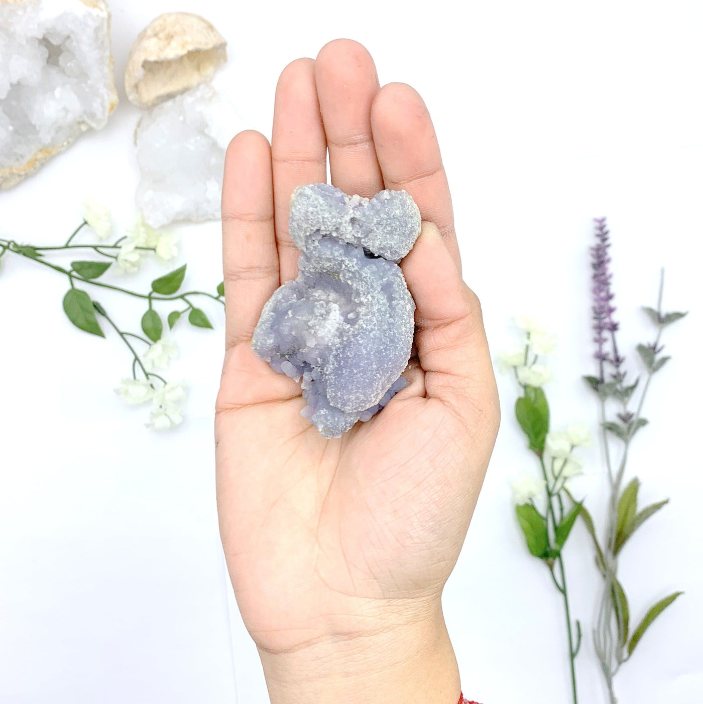 hand holding up Grape Agate Mineral with decorations in the background