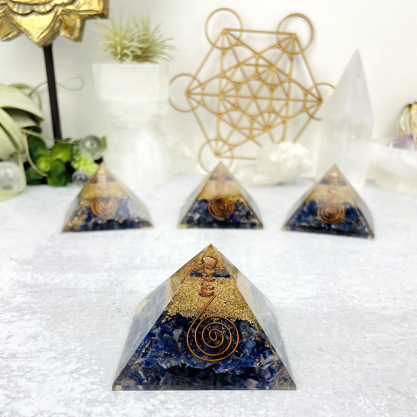 4 Orgone Sodalite with Crystal Point Pyramid displayed, 3 out of focus and 1 in focus.