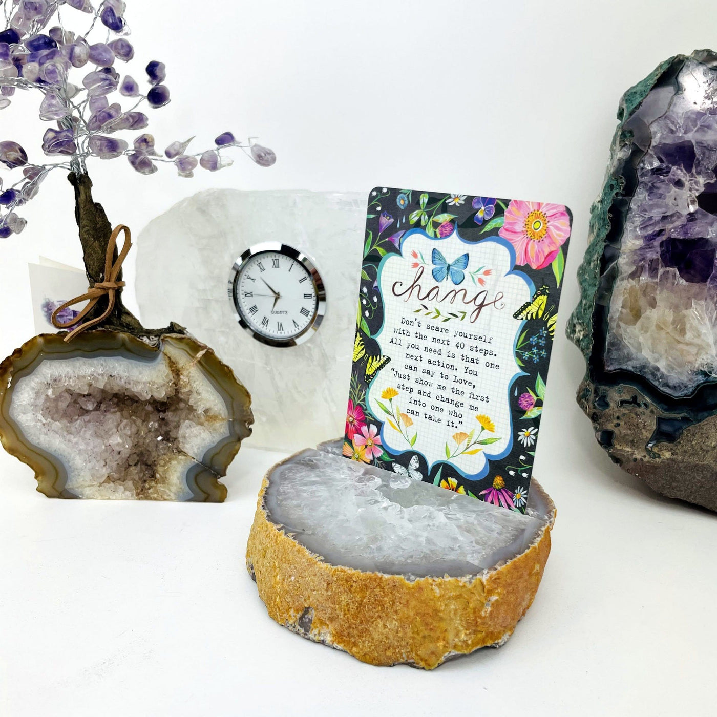 Picture of agate card holder, being displayed next to amethyst tree, selenite clock and white background. 
