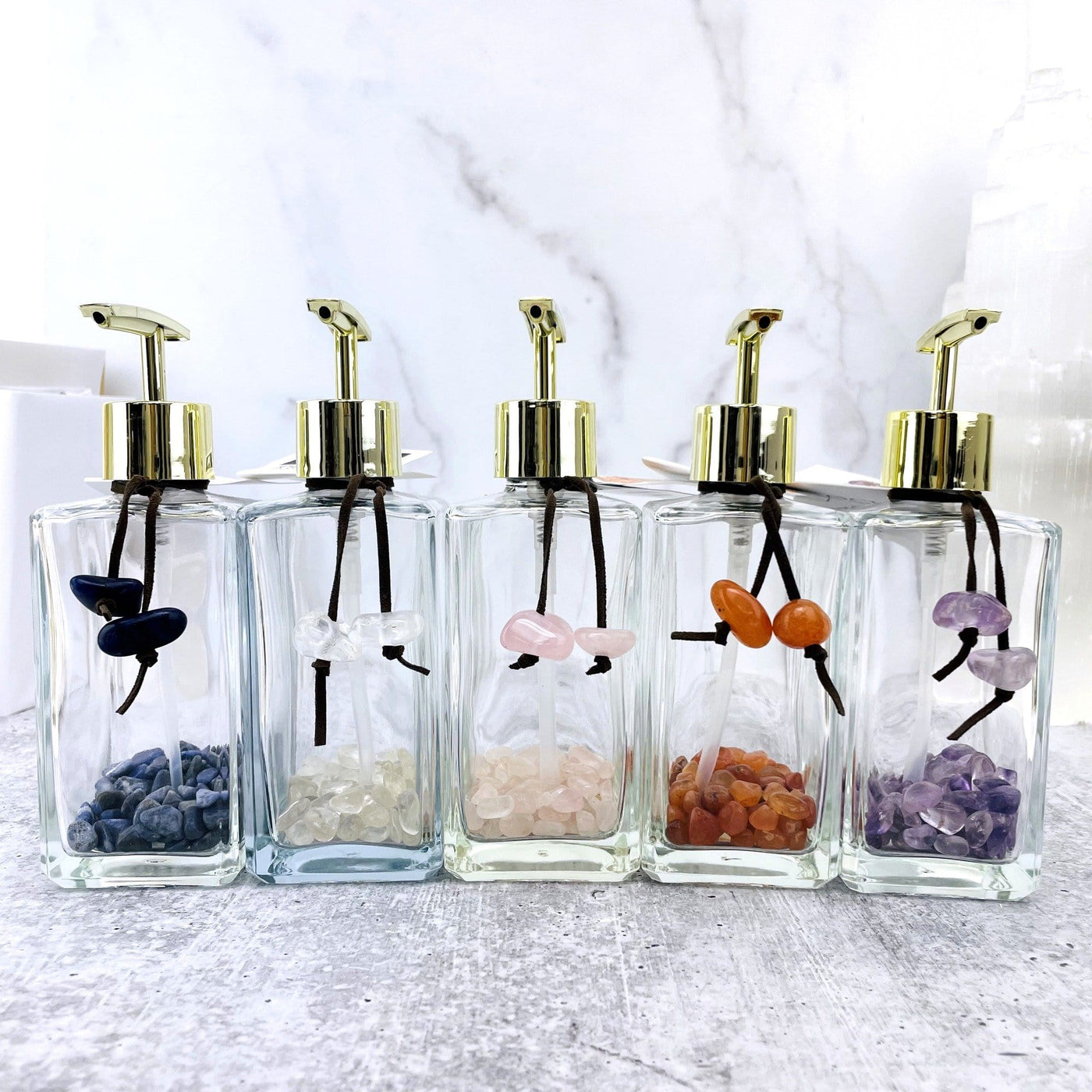 Tumbled Stone Soap Dispensers in a row, one of each stone available, sodalite, crystal quartz, rose quartz, carnelian, and amethyst