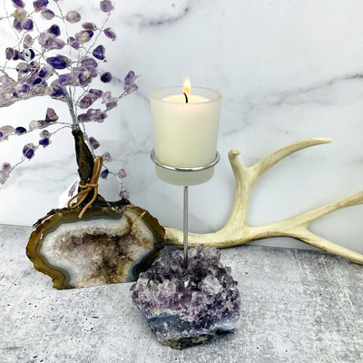 Picture of single amethyst candle holder, next to an amethyst tree. 