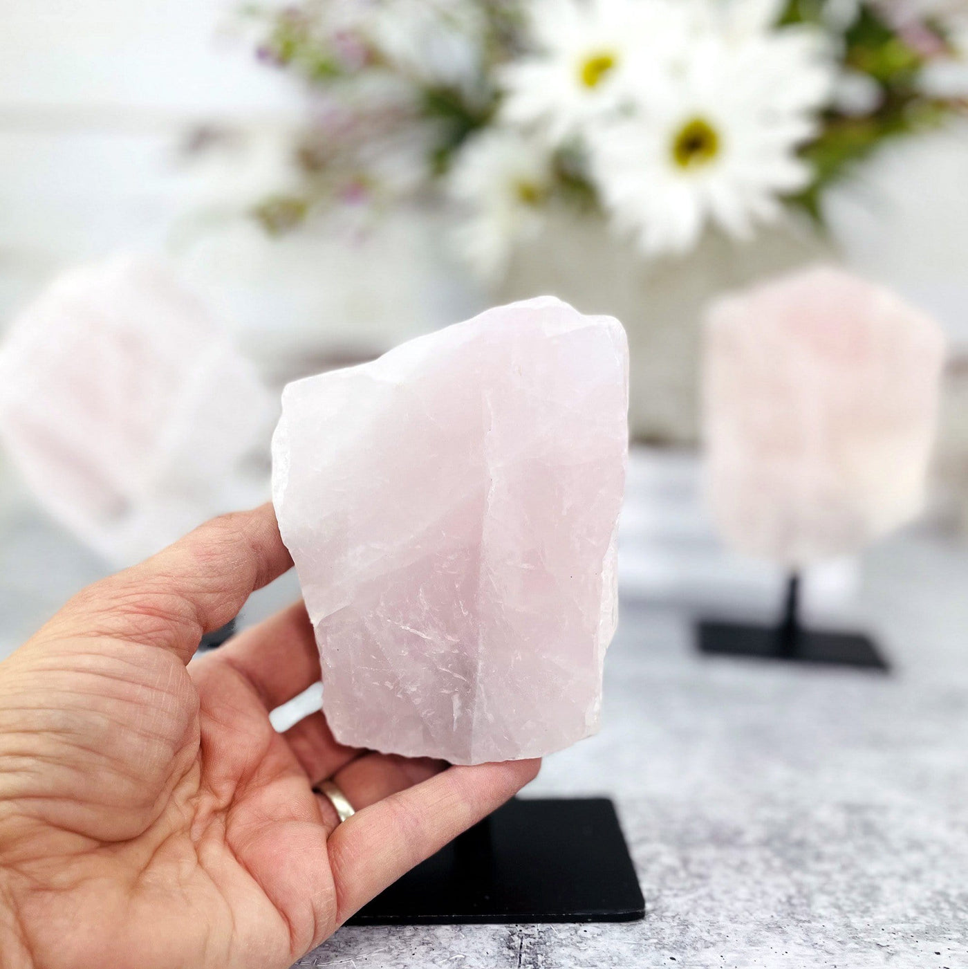 rose quartz on a stand  with a hand holding it