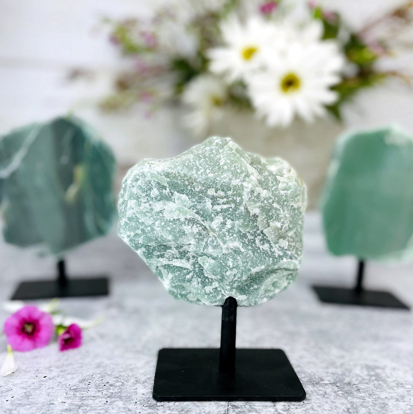 back view of green quartz on metal stand with 2 others blurred in the background