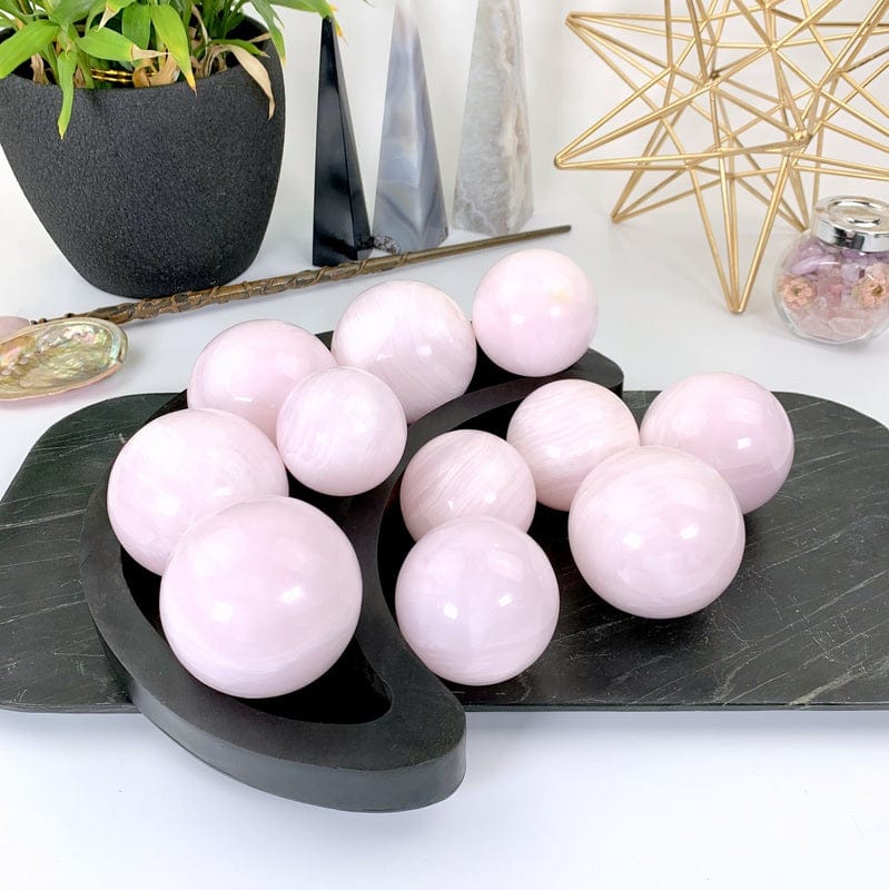 11 pink calcite spheres in a black moon tray