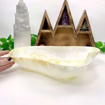 hand next to Mexican Onyx Bowl with decorations in the background